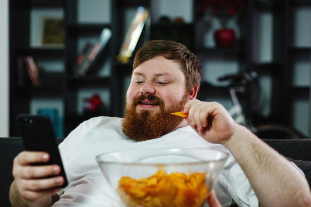 یک مرد چاق درحال چیپس خوردن
